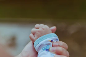 Close-up of a caring hand holding a baby’s hand symbolizing protection for children