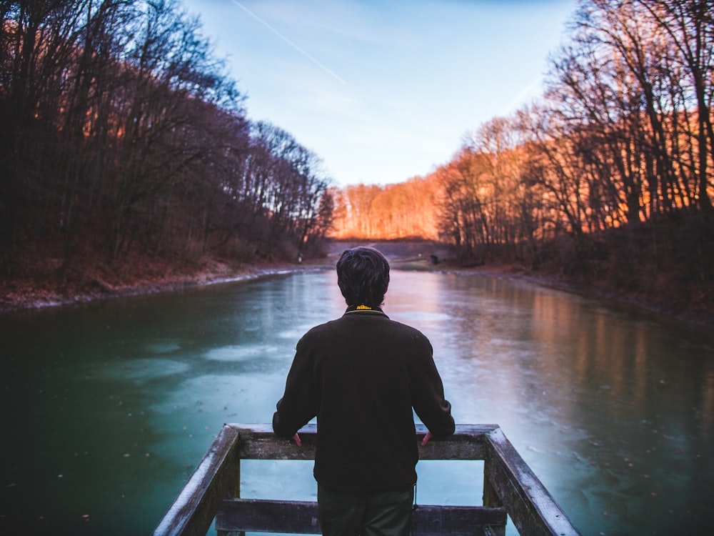 man standing on lake dock