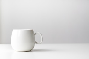 Minimalist composition of a handcrafted ceramic mug on a neutral background.