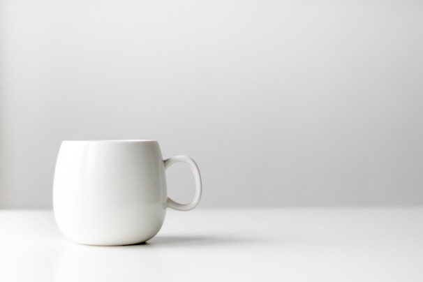 A minimalist ceramic coffee mug and pet water bowl displayed on a clean white surface with soft natural light.