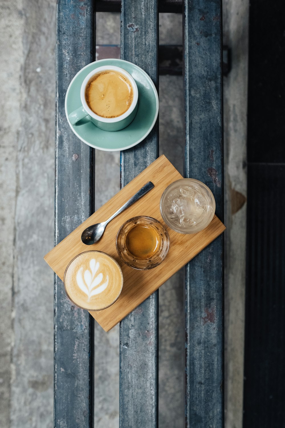 three clear drinking glasses on brown wooden plate beside mug