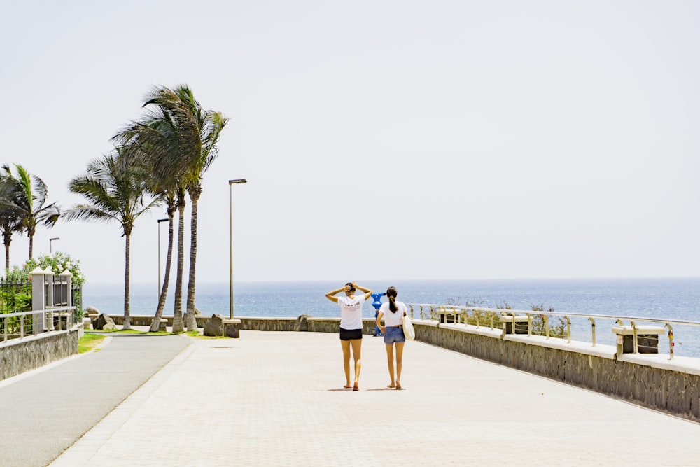 two women walking beside body of water