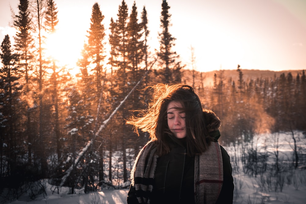 woman in black snow jacket standing in front of pine trees