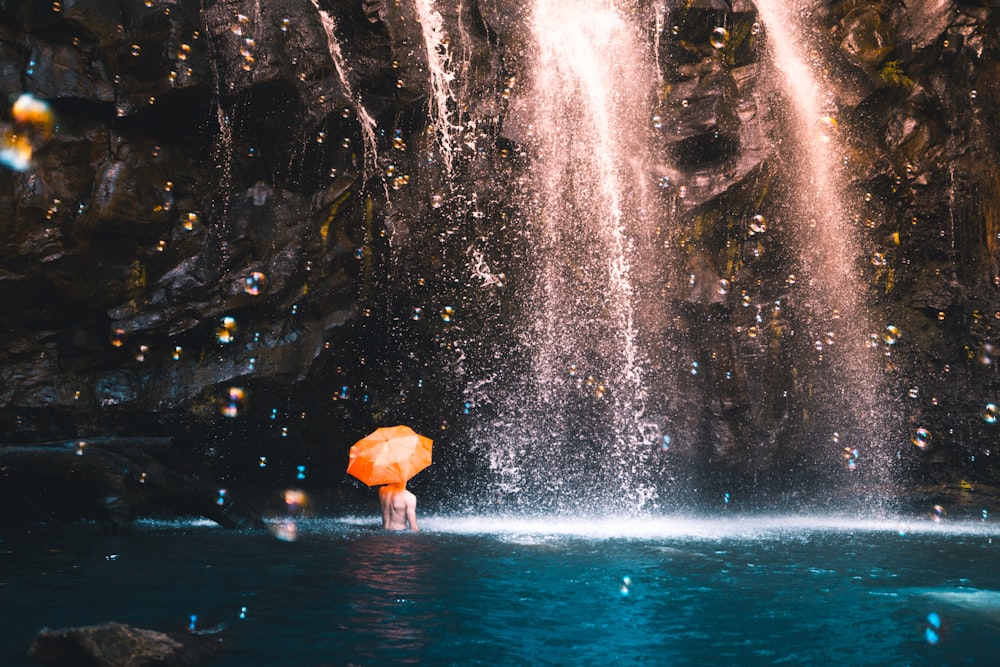 time lapse photography of topless person under waterfalls