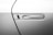 A close-up view of a car door focusing on the sleek, modern handle with a recessed design. The handle is embedded in the car's body, with a minimalist and streamlined appearance, showcasing a metallic finish.