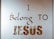 The image contains text on a reflective or translucent surface. The text is stylized and reads 'I Belong to Jesus' in bold and elegant typography. The background appears minimalistic, possibly due to the reflective nature of the surface.