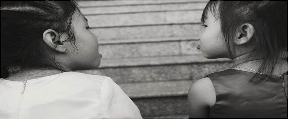 grayscale photography of two girls talking