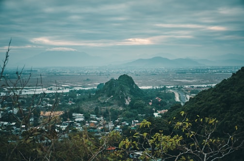 A scenic view of the village landscape with green fields and distant hills.