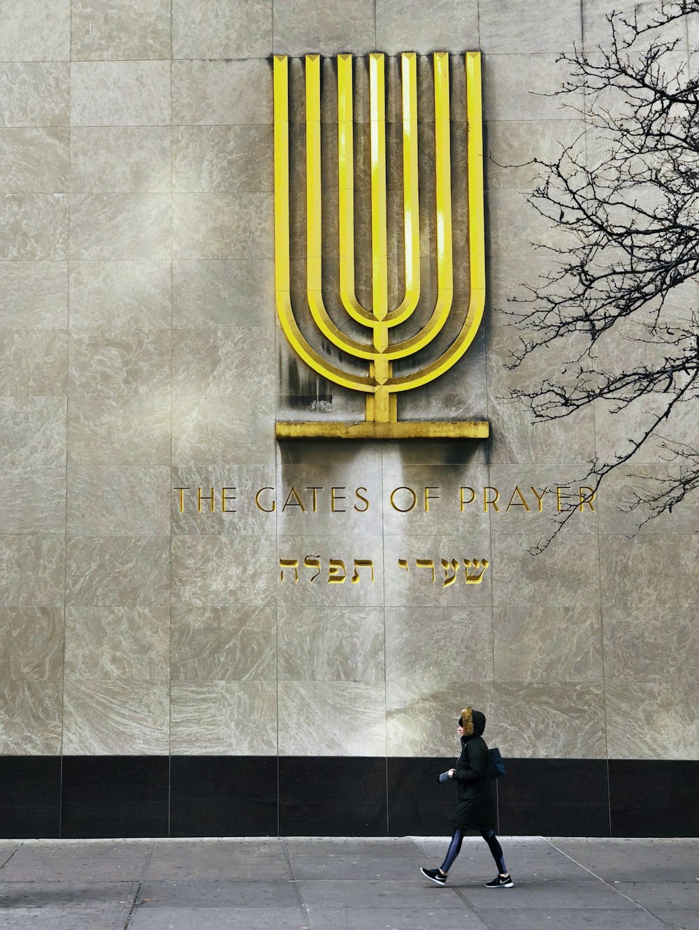 a man walking past a building with a large menorah on it