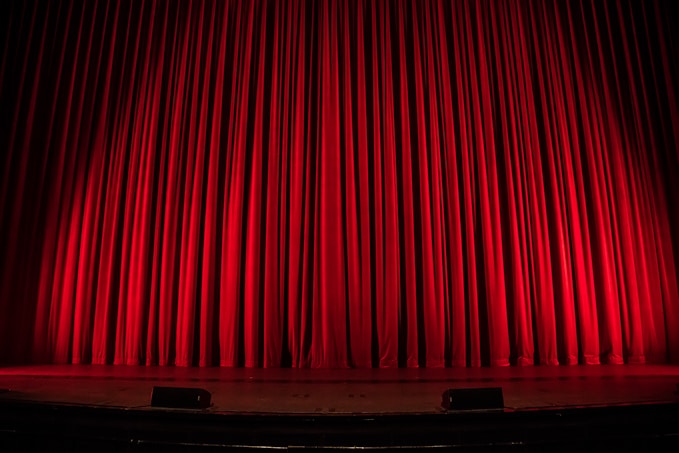 Stage with red curtain and speakers set for a creative performance in UK arts education