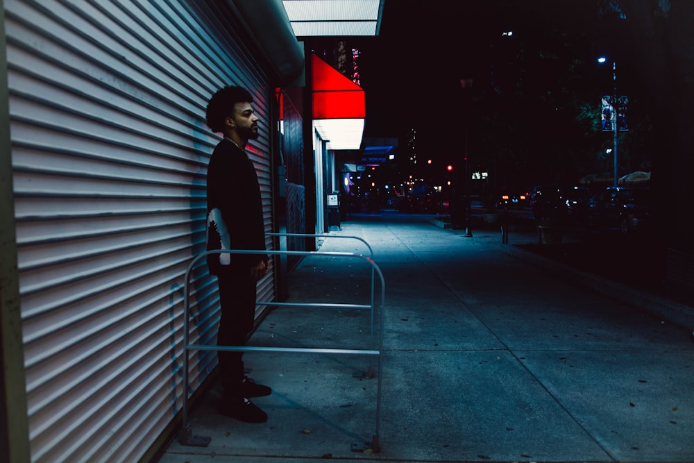 Un homme debout sur un trottoir à côté d’un immeuble
