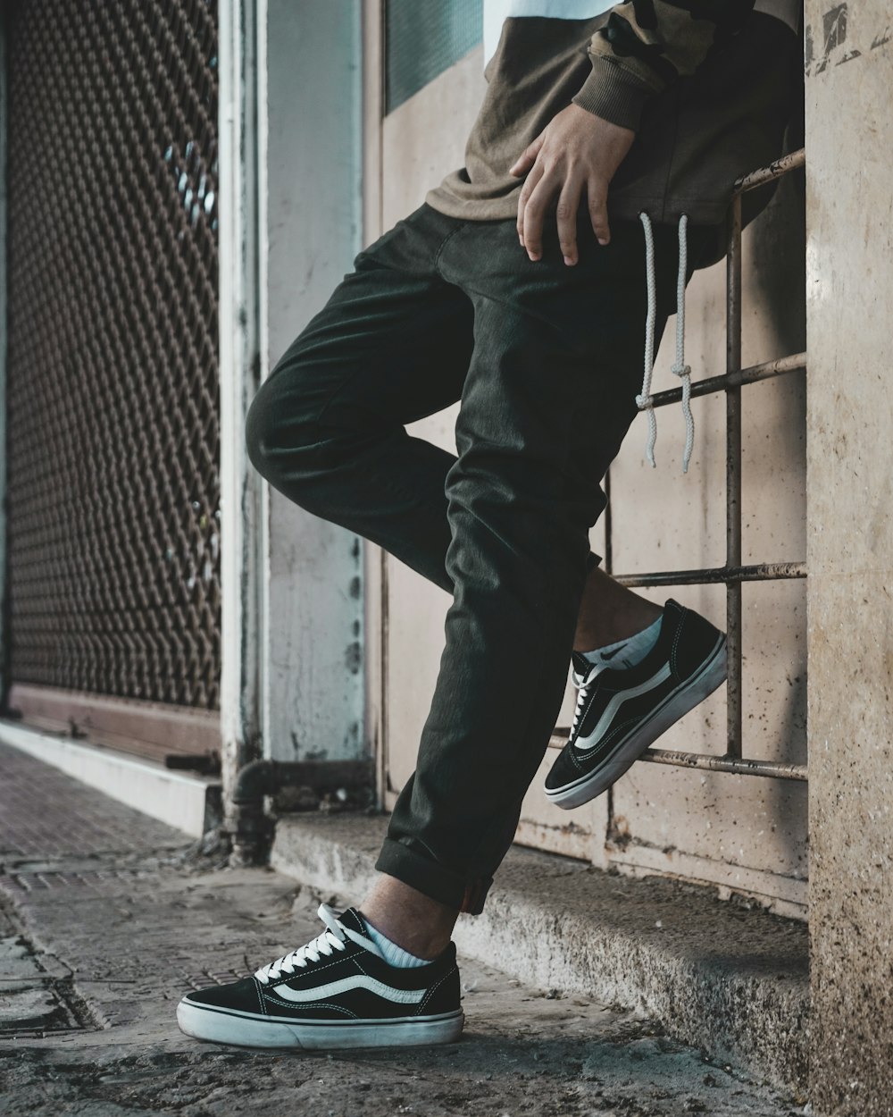 A man leaning against a wall wearing black and white sneakers photo – Free  Clothes Image on Unsplash