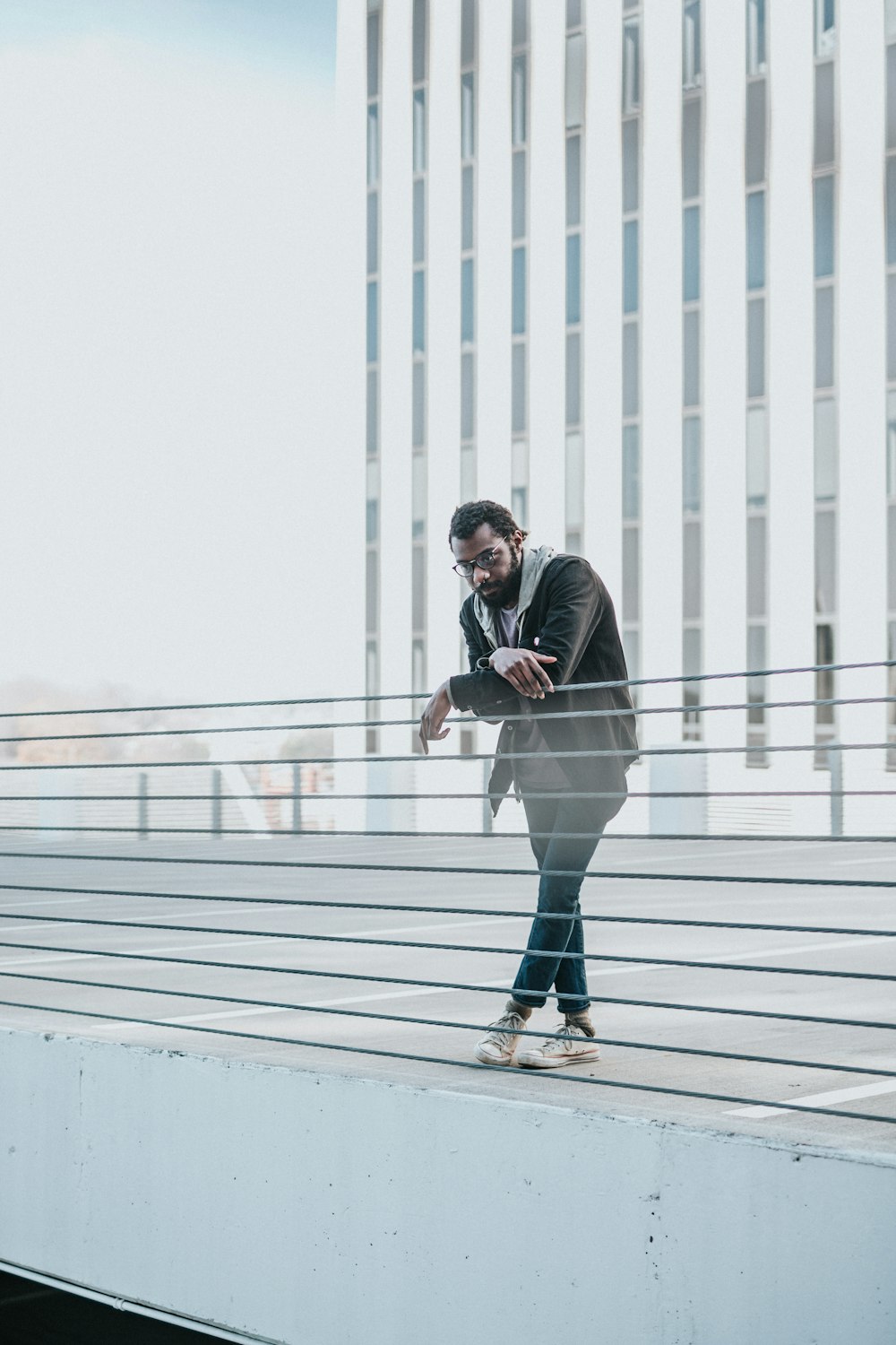 uomo che si appoggia alla recinzione grigia