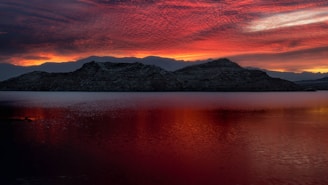 a beautiful sunset over a lake with mountains in the background