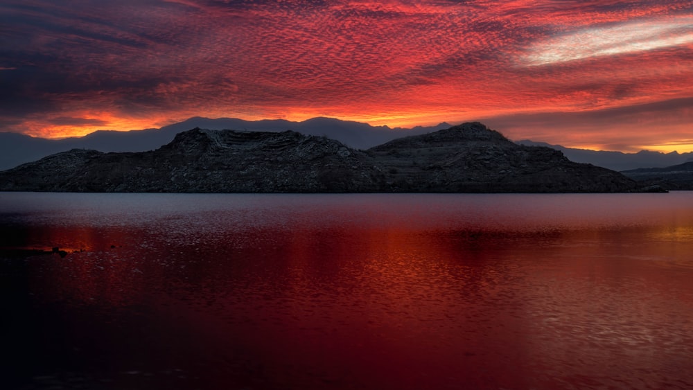 Un beau coucher de soleil sur un lac avec des montagnes en arrière-plan