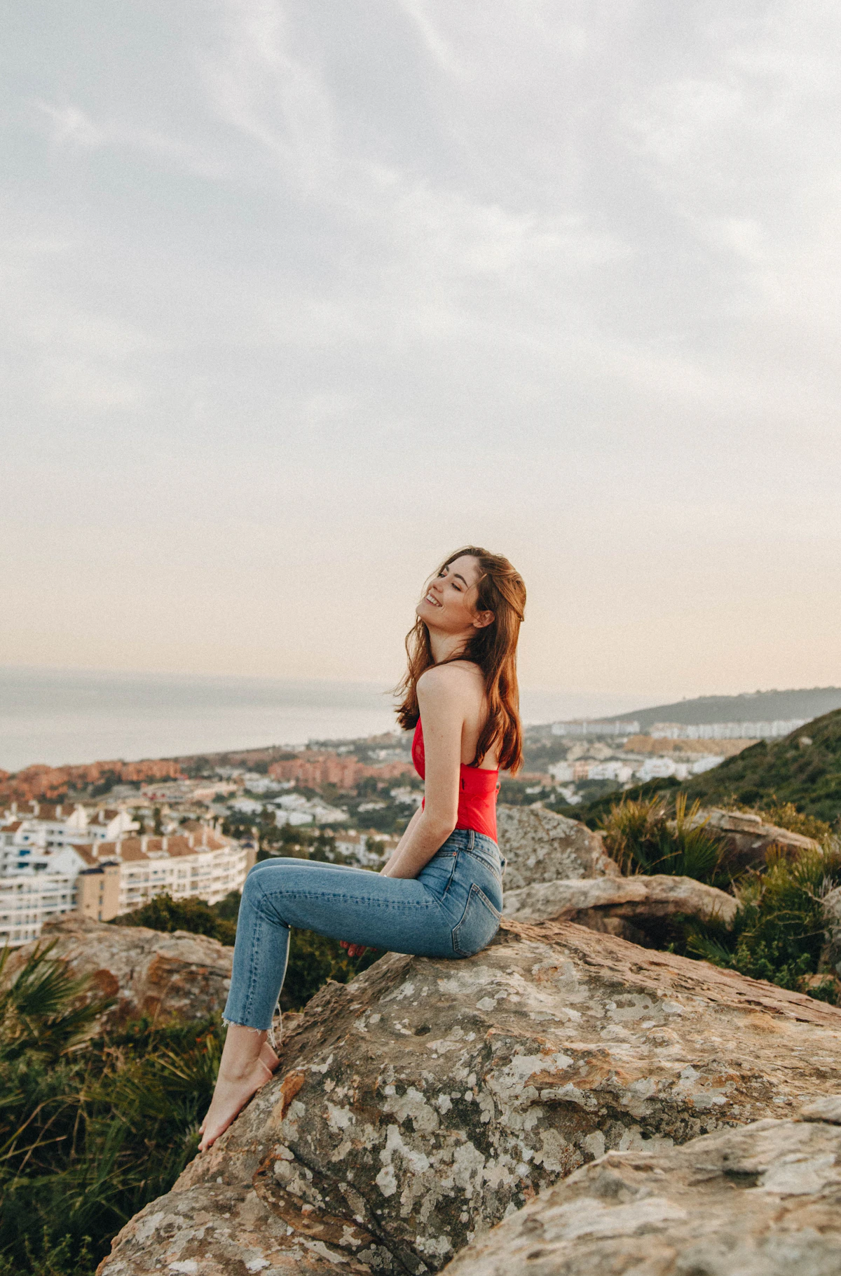 Adult woman in a red top seated calmly above a sunset coast
