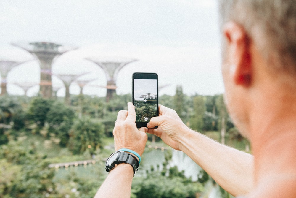 homme prenant une photo à l’aide d’un smartphone pendant la journée