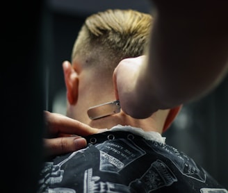 person trimming man's hair