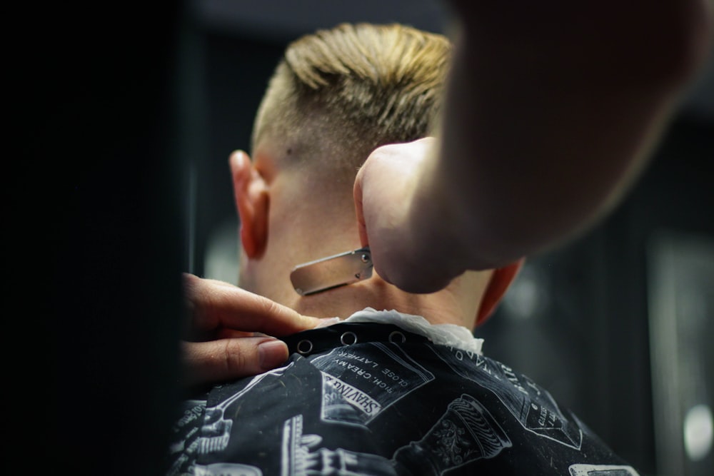 person trimming man's hair