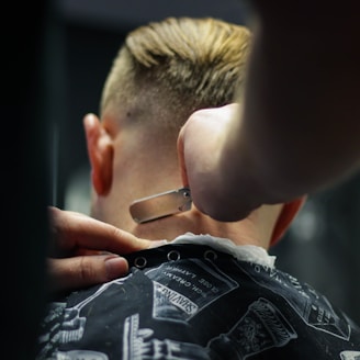 person trimming man's hair