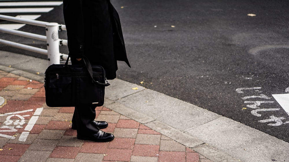 person in black dress shoes beside road