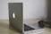 A sleek silver laptop with an illuminated logo sits open on a wooden desk next to a pair of black headphones.