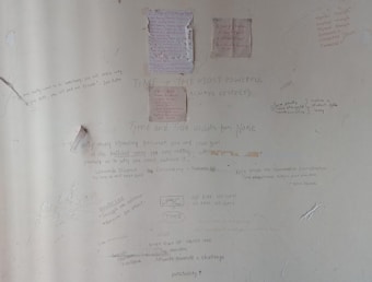 A wall covered in various handwritten motivational quotes and notes. Some quotes are attributed to notable personalities and focus on themes like persistence, success, and self-belief. There are drawings and scribbles, including diagrams and small notes, emphasizing hard work and dedication.