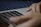 A close-up of hands using a laptop with translation software open.