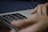 A close-up of hands using a laptop with translation software open.