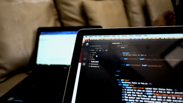 A close-up of hands coding a responsive website on a tablet and laptop.