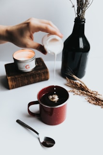 person pouring milk on coffee