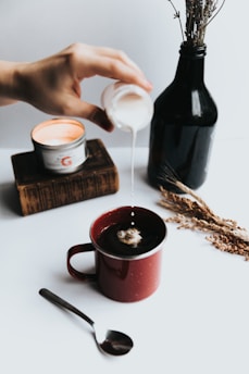 person pouring milk on coffee