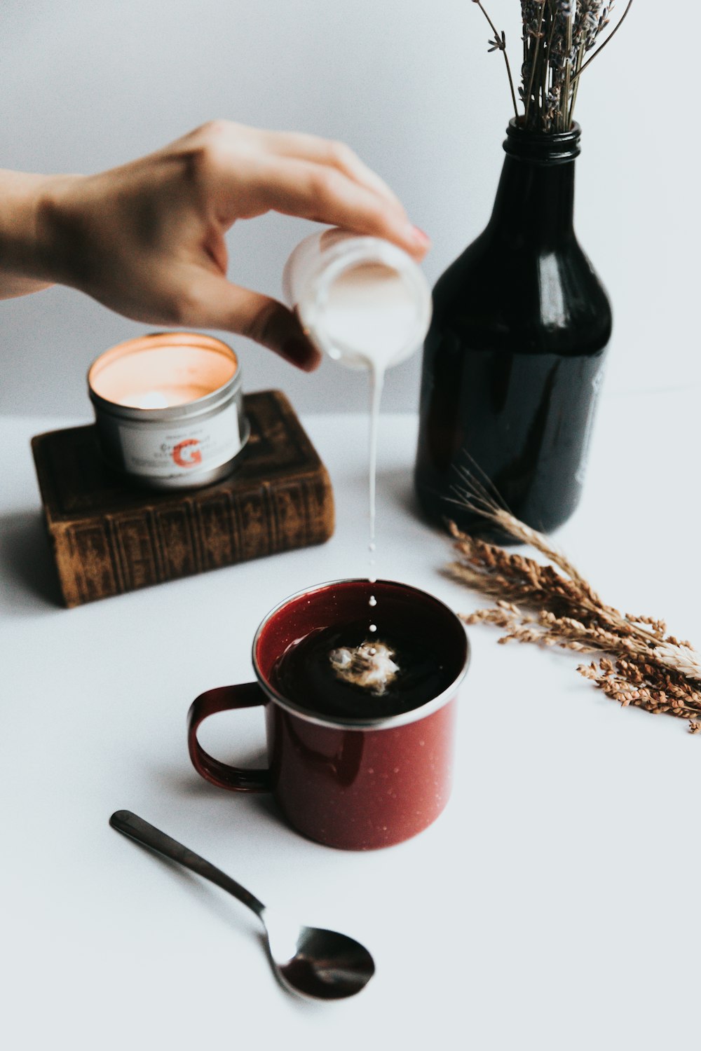 person pouring milk on coffee