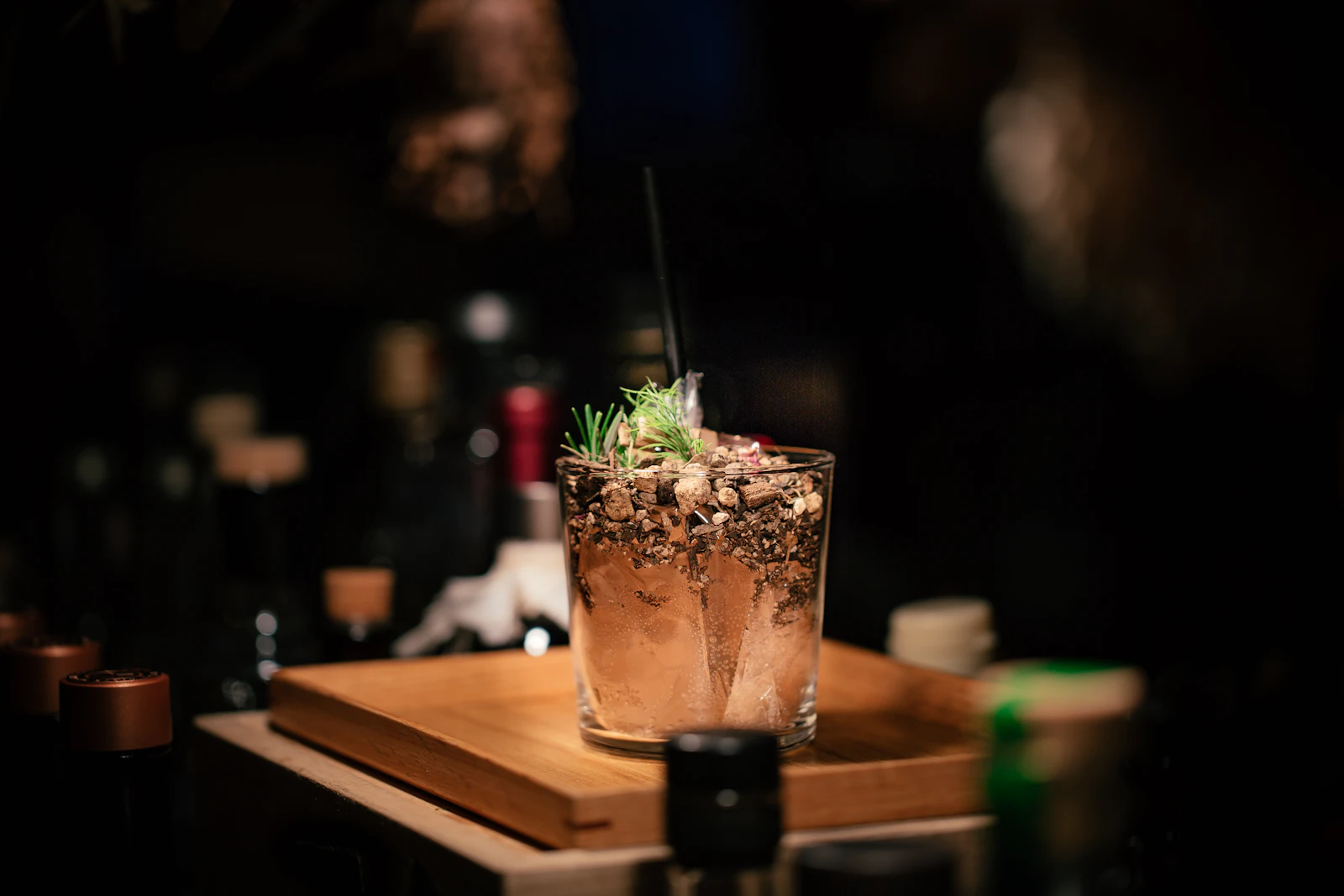 Mano che versa un cocktail ambrato in coppa, sotto una luce calda