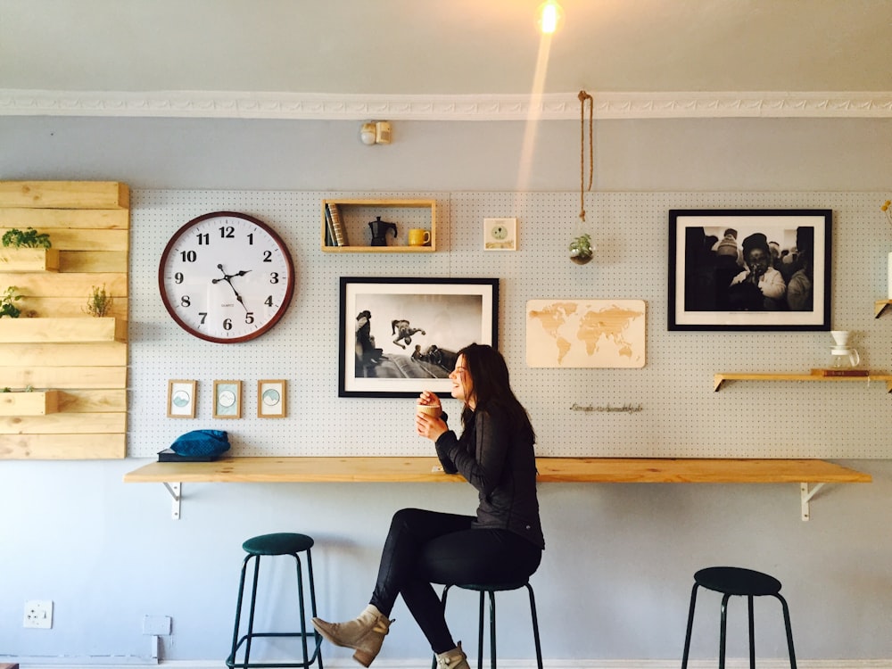 Frau sitzt auf Ständer in der Nähe eines an der Wand montierten Schreibtisches