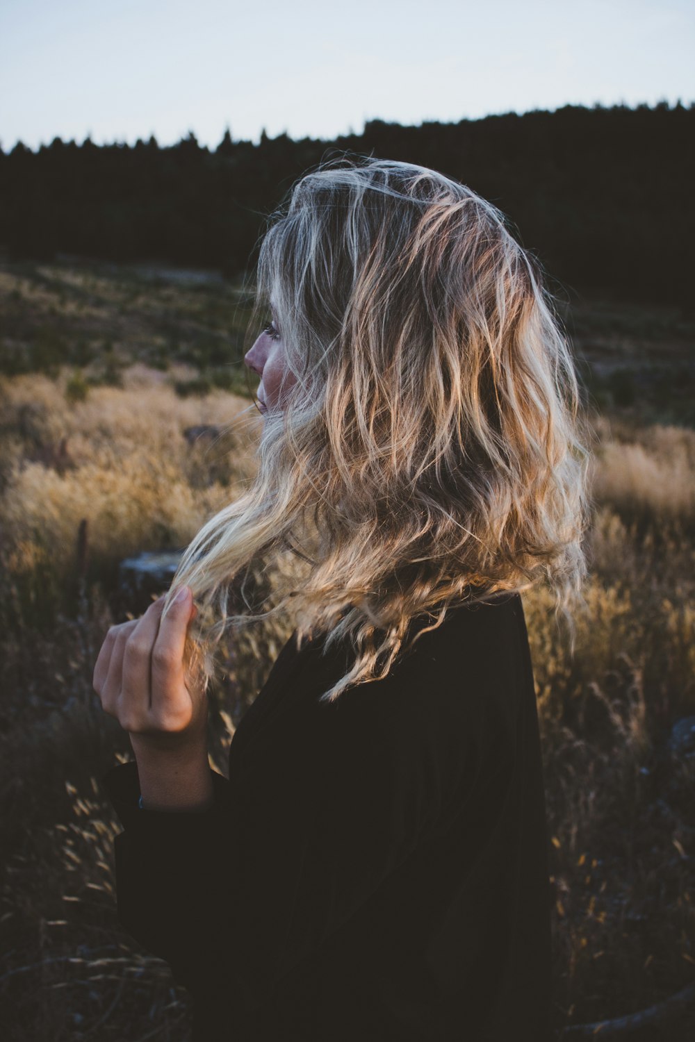 woman holding hair in grass field