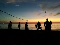 a group of people standing on top of a beach next to the ocean