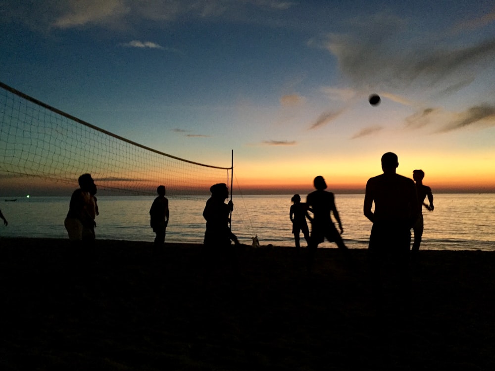 a group of people standing on top of a beach next to the ocean