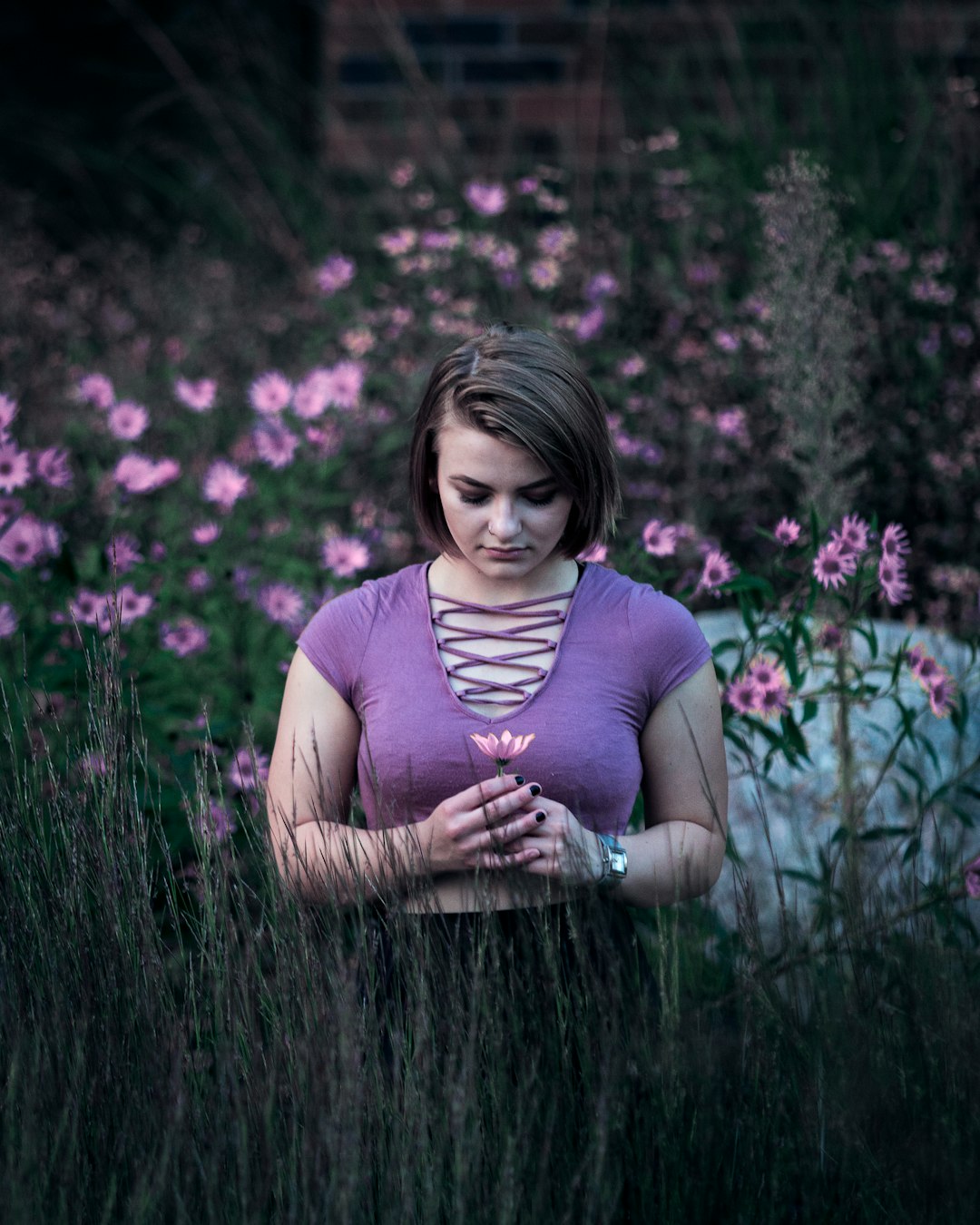 selective focus photo of woman standing on green and pink flower field at daytime