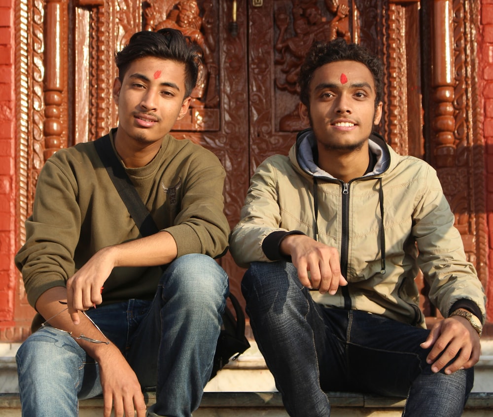 man in brown sweatshirt sitting beside man in brown hoodie near closed brown door