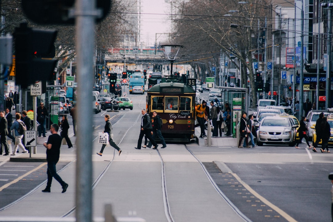 people crossing road near yellow train,