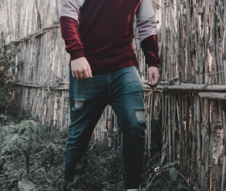 a man standing in front of a bamboo fence