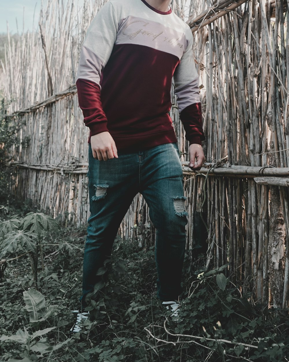 a man standing in front of a bamboo fence