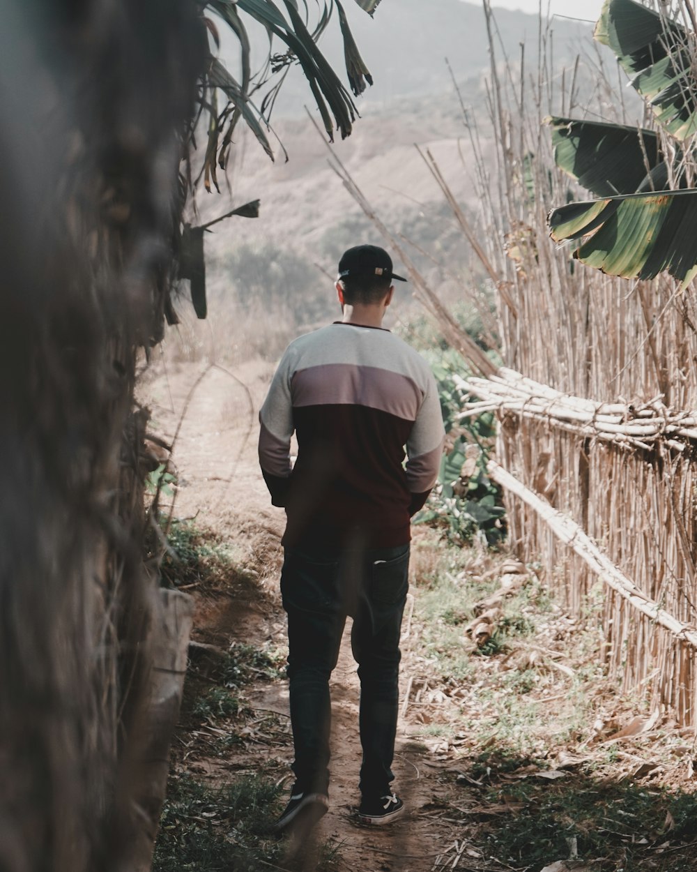 homem no topo branco e preto em pé perto da árvore