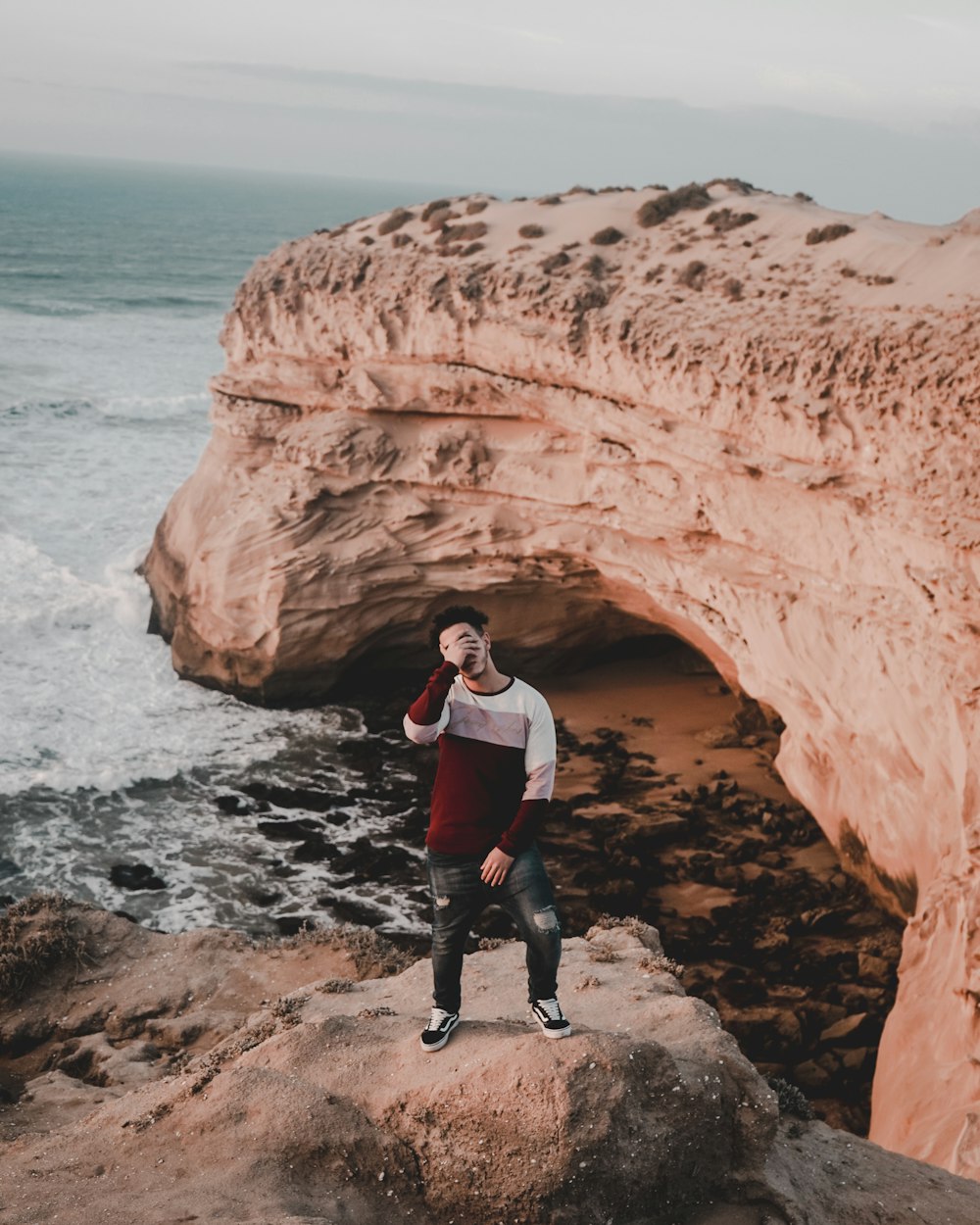 man standing on rock at the shore