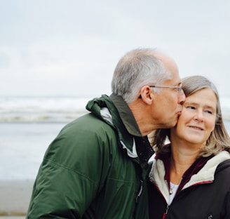 man kissing woman on check beside body of water