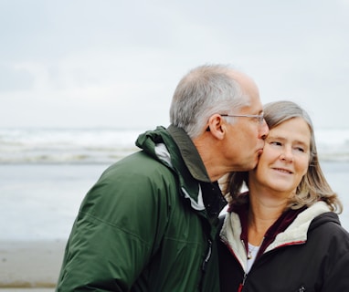 man kissing woman on check beside body of water