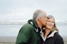 man kissing woman on check beside body of water