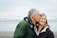 man kissing woman on check beside body of water