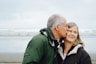 man kissing woman on check beside body of water